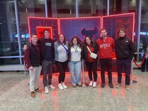 nisivoccia team standing together in front of devils game sign