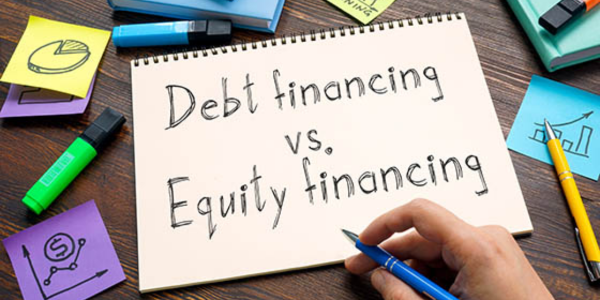 a picture of someone writing debt financing vs. equity financing in a notebook