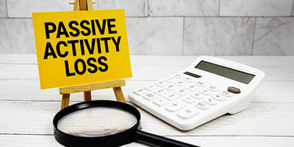 magnifying glass, calculator, and sign that states "passive activity loss" from material participation