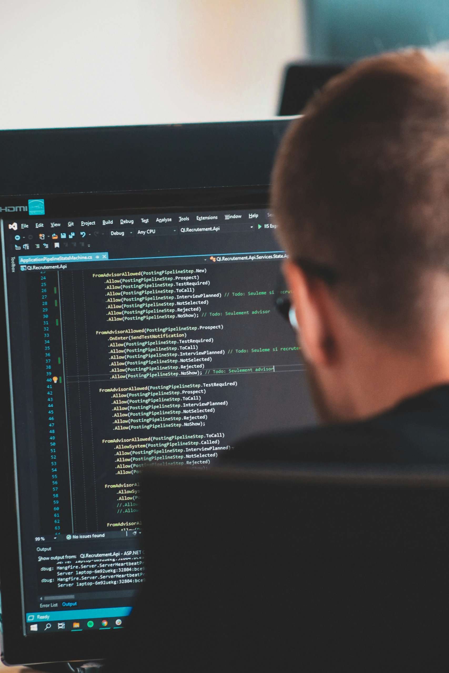 Person viewing lines of code on a computer monitor in a software development environment.