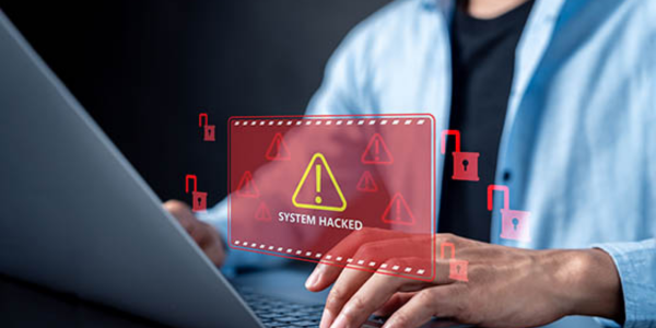 person typing on computer with "system hacked" visible from tax identity theft