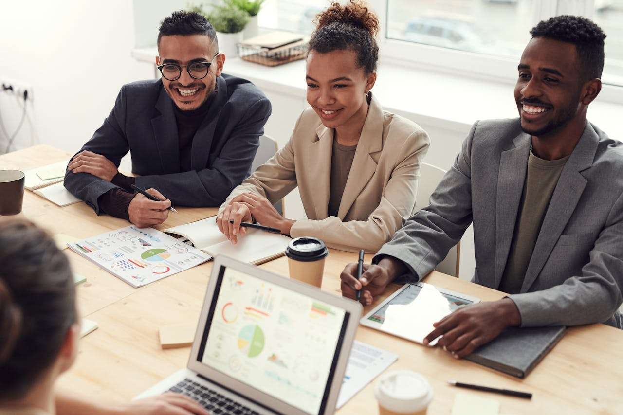 Photo of three people smiling during a meeting.
