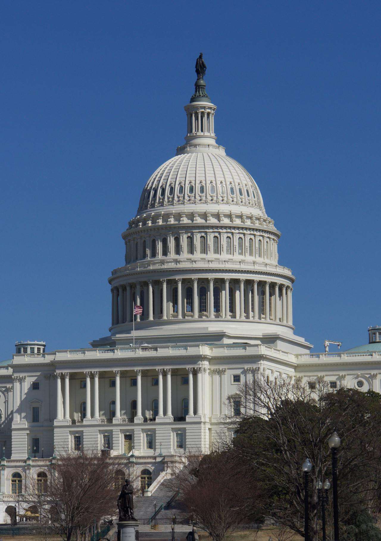 The U.S. Capitol Building in Washington, D.C., with its iconic white dome and neoclassical columns against a clear blue sky.
