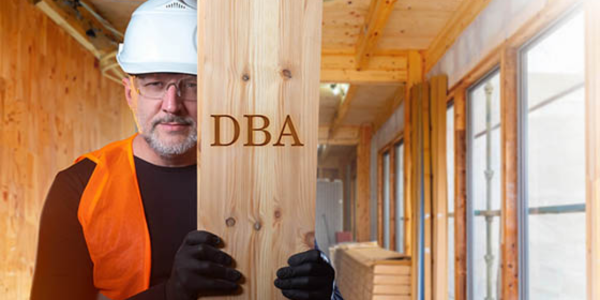 construction contractor holding up wooden board with 'DBA' spelt, referring to DBA filing