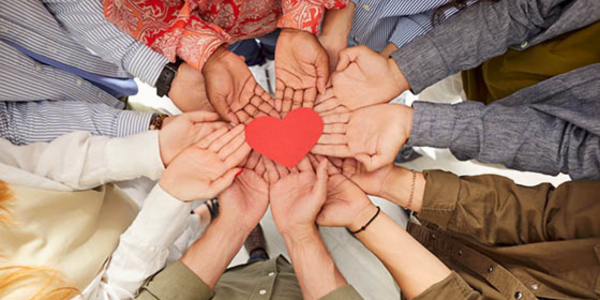 giving circle with hands all put together with a heart over it