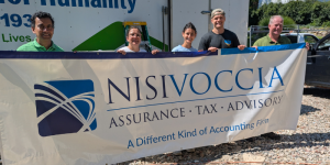 nisivoccia team holding up company banner at habitat for humanity site