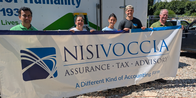 nisivoccia team holding up company banner at habitat for humanity site