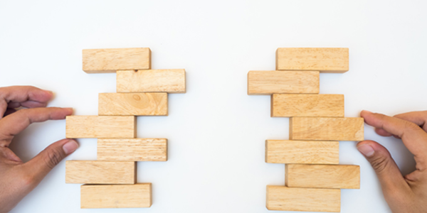 person stacking two columns of building blocks