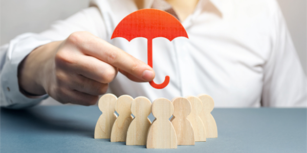 person holding a red wooden umbrella over a group of wooden figures