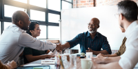 Employees of a nonprofit organization having a conflict-of-interest meeting, with two employees shaking hands while smiling